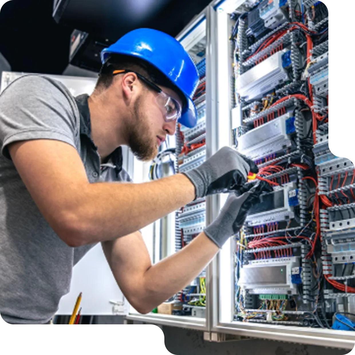 Technician working on an industrial electrical control panel with wiring and components.