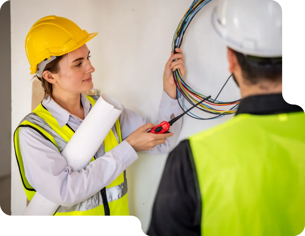 A homeowner working on her laptop while an electrician performs an electrical upgrade in her home.
