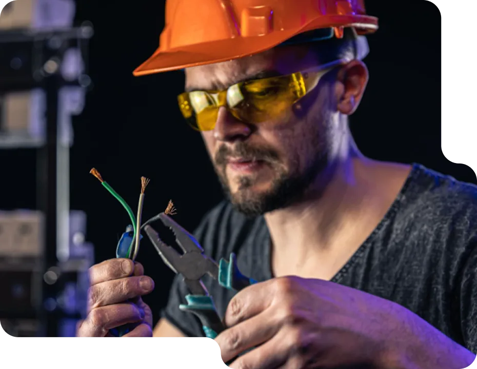 An electrician carefully working on an electrical component with a screwdriver.
