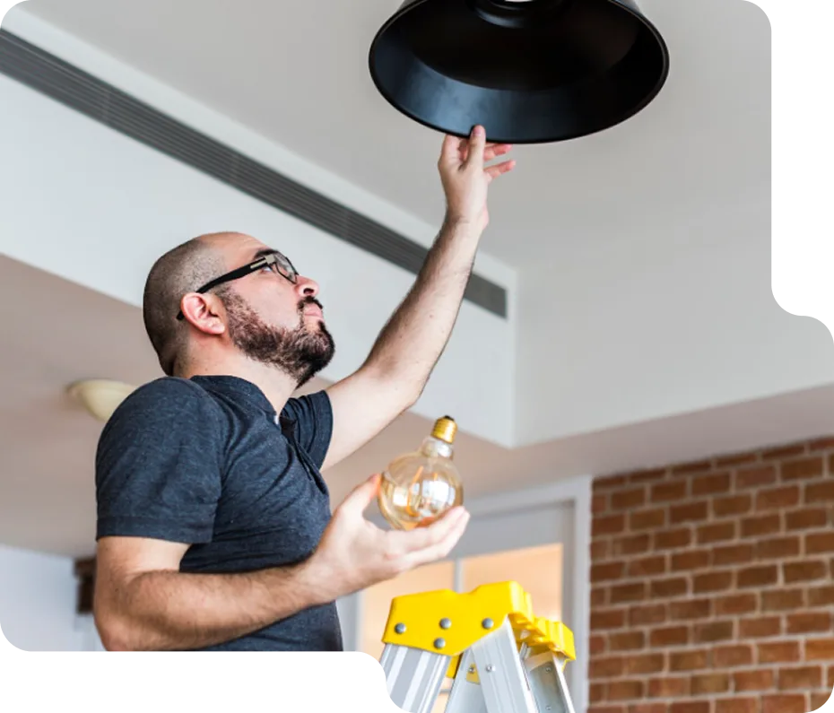 An electrician carefully working on an electrical component with a screwdriver.