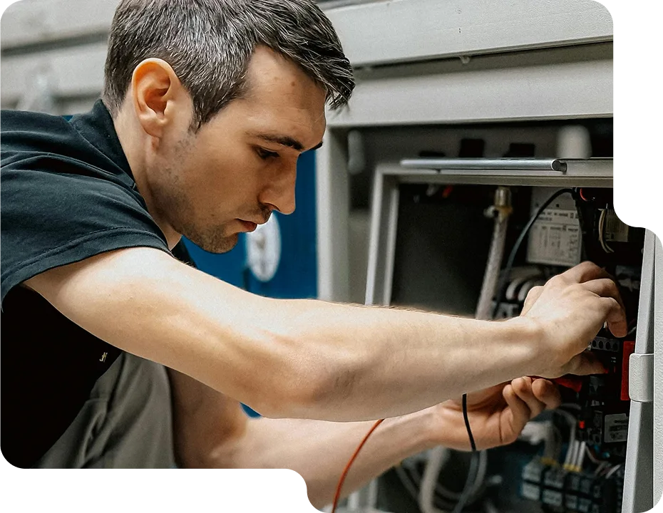 An electrician carefully working on an electrical component with a screwdriver.