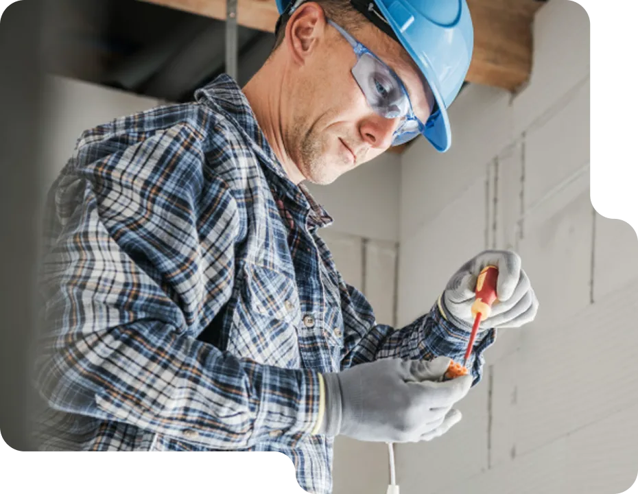 An electrician carefully working on an electrical component with a screwdriver.
